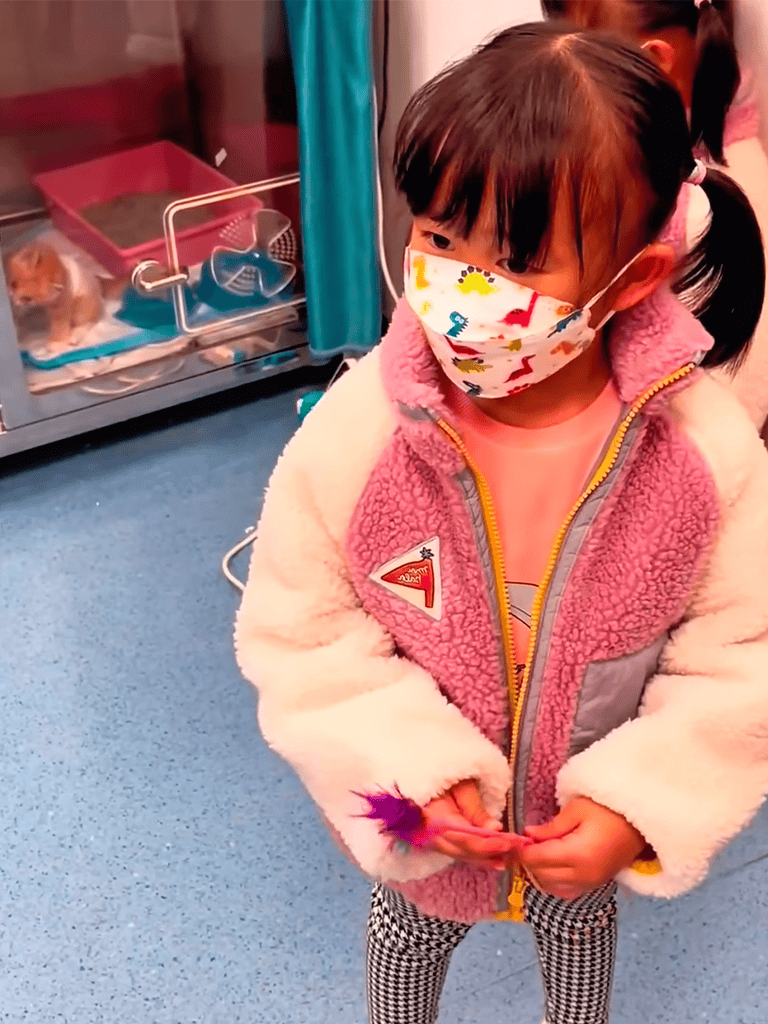Girl wearing colorful face mask and cozy jacket at veterinary pet clinic.