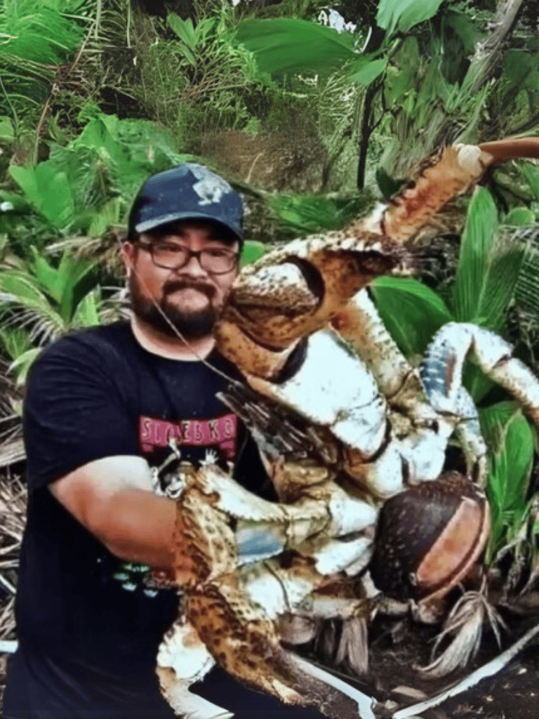 Alt text: Man holding a large otter in lush green jungle environment during wildlife rescue.