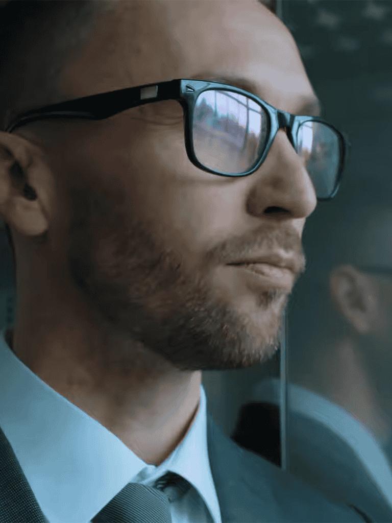 Image of a man wearing glasses and a formal suit, looking thoughtfully outside the window. Perfect for business, professional, or corporate themes.