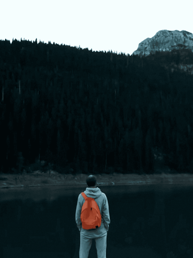Hiker with backpack overlooking mountain lake reflection, serene outdoor scenery.