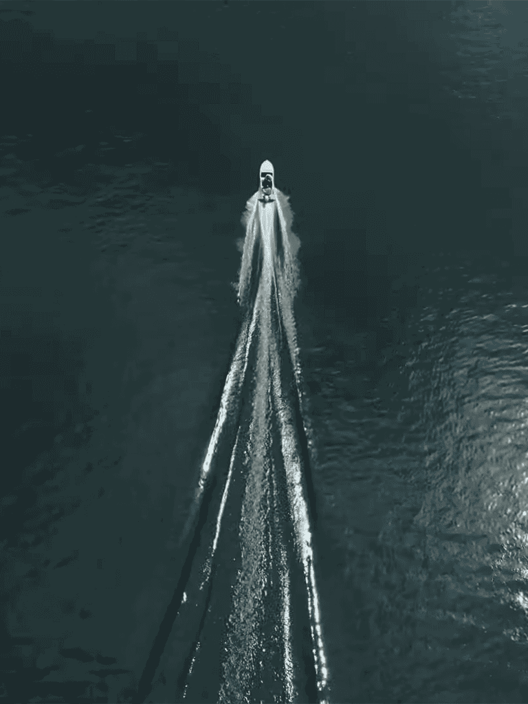 Alt: Speedboat racing on open water with a boat leaving a wake behind it.