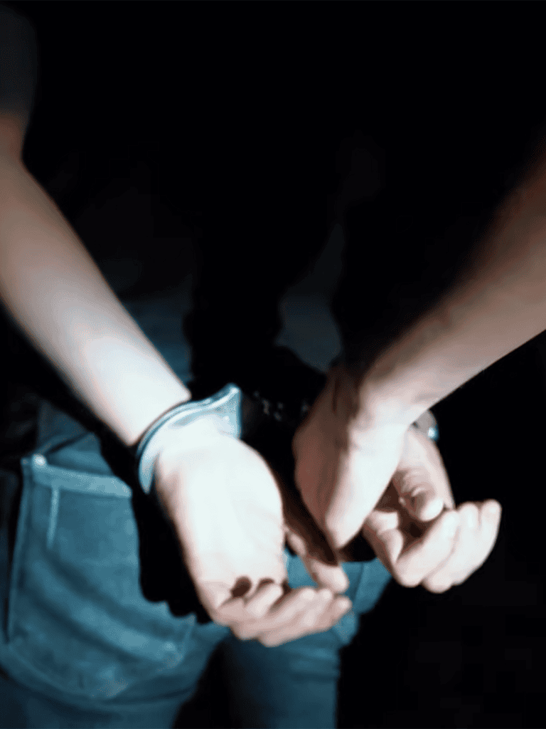 Close-up of hands in handcuffs, arrest image.