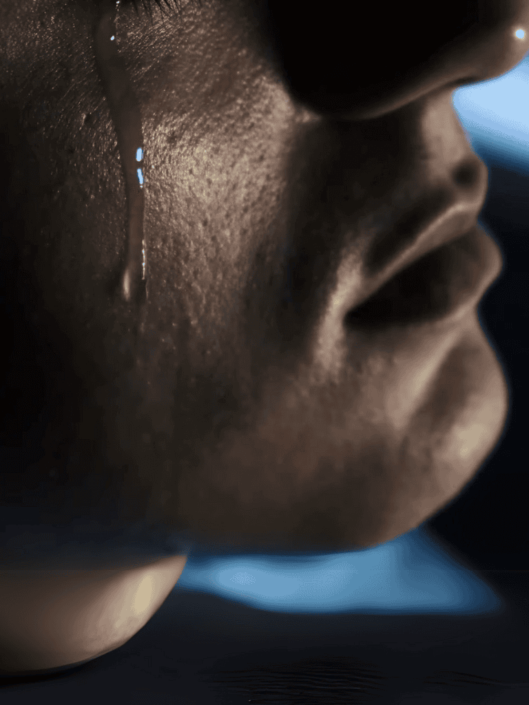 Close-up of a person weeping with tears falling down their face, expressing deep sorrow.