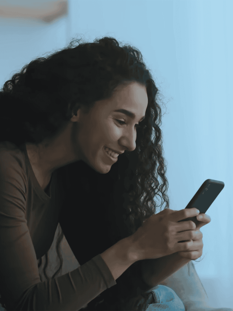 Woman happily browsing on her phone, enjoying mobile communication at home.