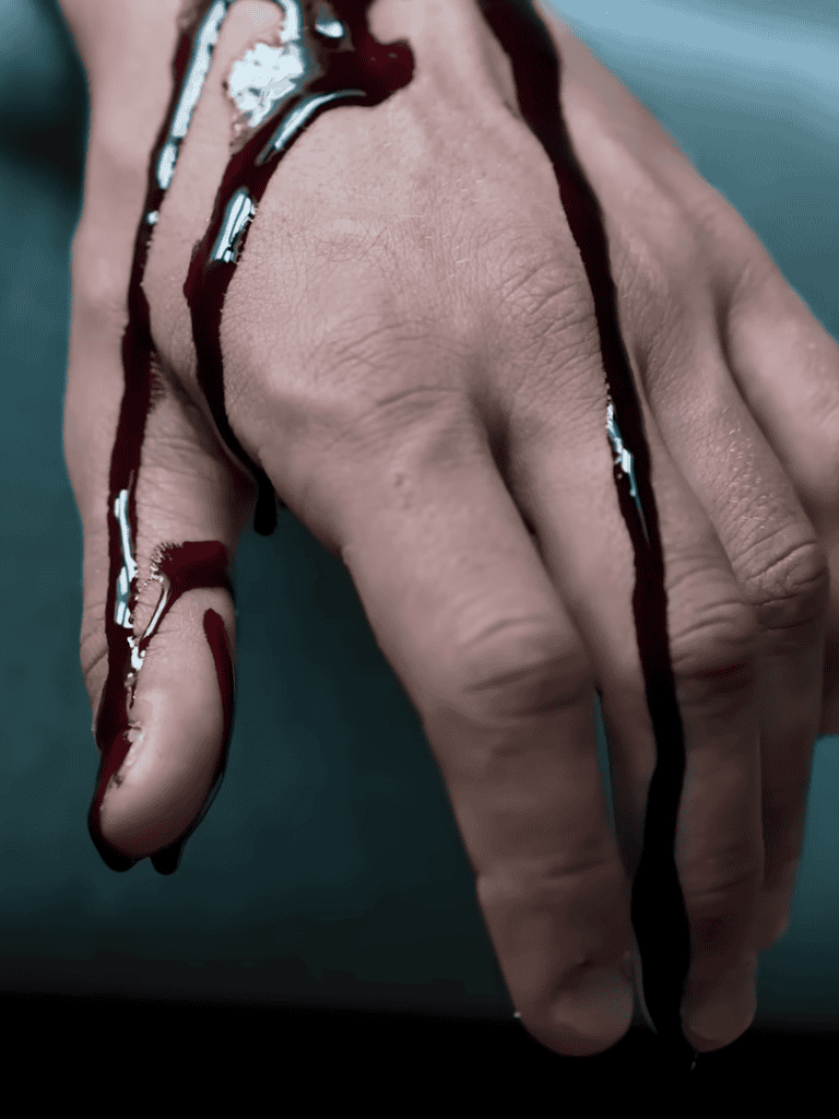 Close-up of a hand with dark, thick liquid dripping down fingers, symbolizing danger or toxicity, on a blurred background.