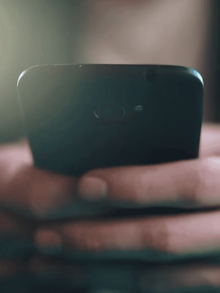 Close-up of a smartphone held in hand, showing the camera lens and design.