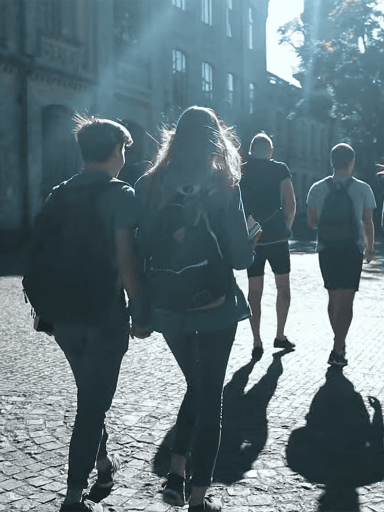 Group of friends walking in city street during sunny day.