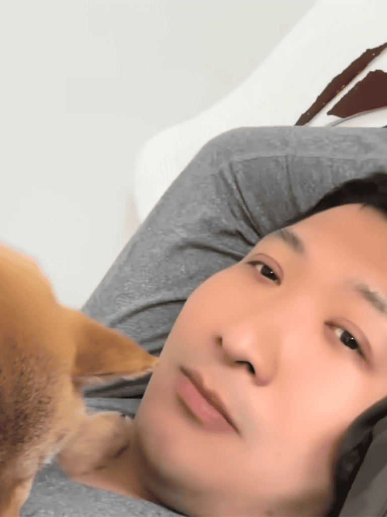 Close-up of a man lying down with a dog on his chest, showcasing a calm and loving pet-human bond.